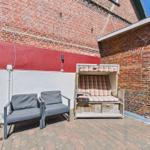 Outdoor area with two seating options and a beach chair against brick walls.