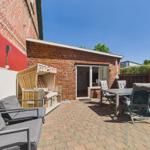 Terrace with seating, lounge, and garden table in front of brick house