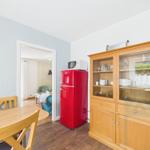 Dining area with wooden table, red refrigerator, and wooden cabinet with dishes.