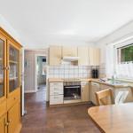 Kitchen with wooden furniture, stove, and window with garden view