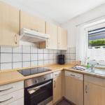 Kitchen with wooden cabinets, stove, sink, and window.