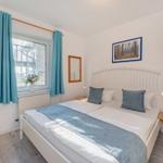 Schlafzimmer mit Doppelbett, blauen Vorhängen und Wandbild.