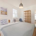 Schlafzimmer mit Bett, Nachttisch, Wandbild und Blick in Wohnbereich.