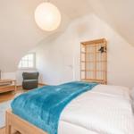 Schlafzimmer mit Bett, Kleiderschrank und Fernseher unter Dachschrägen.