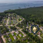 Luftbild eines Ferienorts mit Häusern, Wald und Wasser. Ein Haus ist markiert.