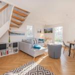 Wohn- und Essbereich mit Holzfußboden, Treppenhaus und moderner Einrichtung.