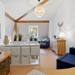 Living room with sofa, TV, and wooden floor. Attic structure with wooden beams.
