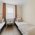 Zwei Einzelbetten mit Tisch und Fenster im Zimmer.