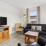 Wohnzimmer mit Sofa, Fernseher und Fenster