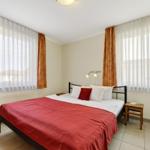 Schlafzimmer mit Doppelbett, zwei Fenstern und Holztisch