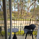 Balkon mit Tisch und Stuhl, Blick auf Wald und Strand.