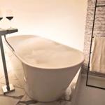 Freistehende Badewanne mit Schaum, zwei Weingläser und Handtuchhalter.