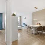Wohnung mit Essbereich, Schlafzimmer und Wohnzimmer. Holzboden, weiße Möbel und moderne Beleuchtung.