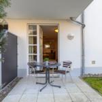 Terrasse mit Tisch und Stühlen, Blick in die Küche.