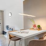 Essbereich mit weißem Tisch und beigen Stühlen, daneben Wohnbereich mit TV und Fenster.