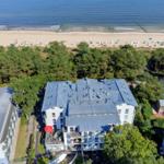 House with balcony, beach and forest in background