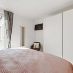 Schlafzimmer mit Bett, Fenster, Kleiderschrank und Sessel.