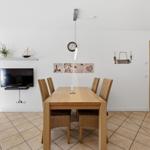 Essbereich mit Holztisch, vier Stühlen und Fernseher an der Wand.