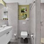 Badezimmer mit Dusche, Toilette und Waschbecken. Wandgestaltung mit Bildern von Blumen.