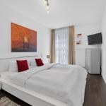 Schlafzimmer mit Doppelbett, Wandbild und Fernseher.