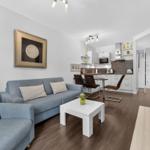 Wohnzimmer mit Sofa, Couchtisch und offener Küche im Hintergrund.