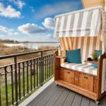 Balcony with beach chair, view of river and sky.