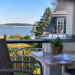 Balkon mit Sicht auf See und Garten. Tisch, Stühle und Pflanze sind sichtbar.