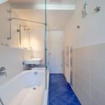 Badezimmer mit Badewanne, Dusche, Waschbecken und Heizkörper.