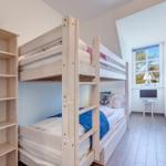 Zimmer mit Doppelstockbett, Regal und Fenster mit Blick nach draußen.