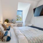 Schlafzimmer mit Dachfenster, Bett, Fernseher und Schrank.