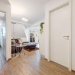 Wohnung mit Wohnzimmer, Schlafzimmer und Flur. Holzdielen, Sofa, TV und Dekoration.