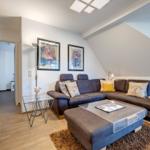 Wohnzimmer mit Sofa, Couchtisch und Wandbildern unter Dachschräge.