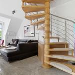 Living room with spiral staircase, leather sofa, and balcony view.