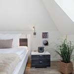 Bedroom with sloped ceiling, bed, nightstand, and plant
