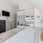 Bedroom with bed, mirrored wardrobe, and TV mounted on the wall.