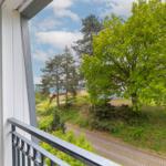 Balcony with view of green trees and a paved path.