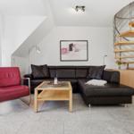 Living room with brown sofa, red chair, and wooden staircase.