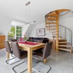 Dining area with table, chairs, and spiral staircase.