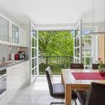 Kitchen with dining area, balcony, and view of green trees.
