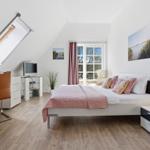 Bedroom with sloped ceiling, bed, desk, and TV.