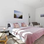 Bedroom with bed, armchairs, and wall art.