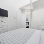 Bedroom with bed, wardrobe, and wall-mounted TV