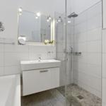 Bathroom with shower, sink and bathtub. White tiles and modern fixtures.