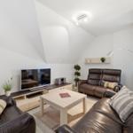 Living room with brown leather sofas, TV, table and glass wall