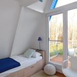 Ein Schlafzimmer mit Dachschrägen, Bett, Stuhl und Balkon mit Blick in den Wald.