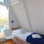 Ein Schlafzimmer mit Dachschrägen, Bett, Stuhl und Fenster zum Balkon.