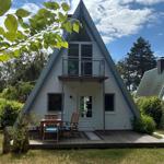 A-frame-Haus mit Balkon und Terrasse im Garten. Holztisch und Stühle.