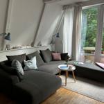Ein Wohnzimmer mit grauem Sofa, Holzboden und Blick auf einen Garten.
