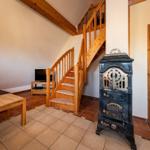 Wohnzimmer mit Holztreppe, Kaminofen und Sofa auf Terrakottboden
