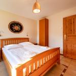 Schlafzimmer mit Holzbett, Nachttisch, Kleiderschrank und Holztür.